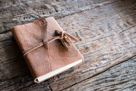 Foto de El libro de cuero en la mesa de madera. Un cuaderno es un pequeño libro para escribir notas en. - Imagen libre de derechos