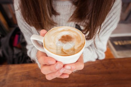 Photo for Women holding a cup of hot Cappuccino coffee in her hand. - Royalty Free Image