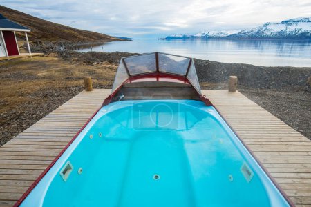 Téléchargez les photos : Un bain à remous bateau emblématique à l'extérieur de la maison d'hôtes locale de Mjoeyri près d'Eskifjordur ville du fjord est de l'Islande. - en image libre de droit