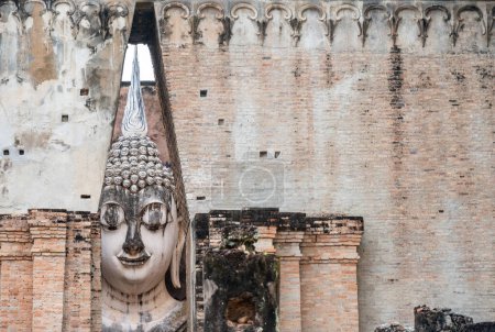 Foto de Pintoresca vista de una enorme estatua icónica de Buda dentro de un edificio techado del templo de Wat Si Chum ubicado en la zona norte del Parque Histórico de Sukhothai fuera de la ciudad amurallada. - Imagen libre de derechos