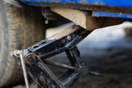 Photo for Defocus closeup of a car lifted on jack in process of new wheel tire replacement. Car jack. Lifting a car with spanner jack-screw. Out of focus. - Royalty Free Image