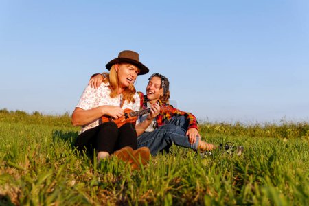 madre e hija cantan alegremente juntas mientras tocan el ukelele en un día soleado de verano, capturando la esencia del vínculo familiar y el disfrute musical al aire libre.