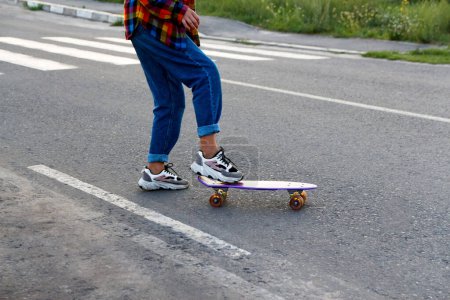 Ein rebellischer Teenager skatet auf einem städtischen Zebrastreifen, trotzt den Verkehrsregeln und verleiht Straßensammlungen oder Artikeln über urbane Jugendkultur eine kantige Atmosphäre..