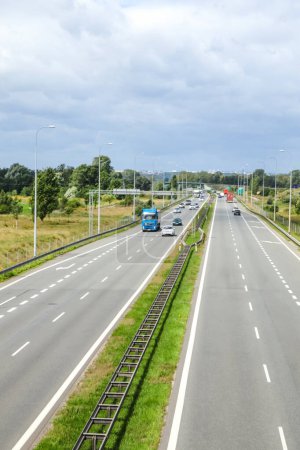 Carretera. Vertical. Autopista ocupada con coches y camiones que viajan en dos carriles, que ilustran el viaje diario y la red de transporte, ideal para anuncios de la industria automotriz.
