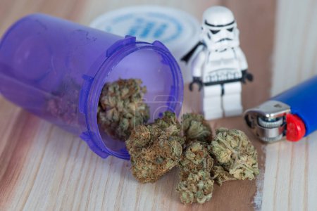 Téléchargez les photos : Hybride sur le côté dominant Indica Skywalker OG Medicinal Medical Marijuana avec Storm Trooper, briquet bleu et flacon de médecine en plastique violet. - en image libre de droit