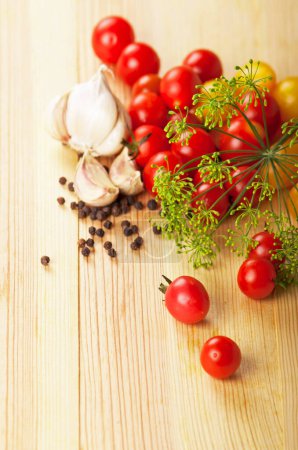 Photo for Cherry tomatoes, garlic, spices, a fennel branch on a kitchen board - Royalty Free Image