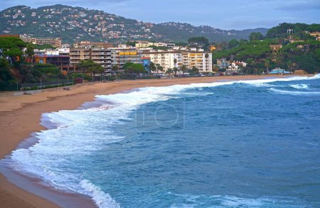 Fenals Beach, Lloret de Mar Spain. Top view of a deserted beach in cloudy weather, blue, turquoise, thick water, green vegetation, storm at sea.