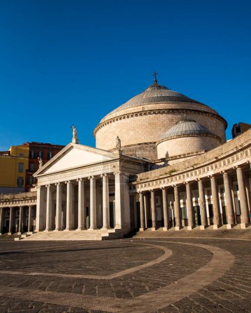 The piazza del plebiscito in naples, italy, with its historic architecture and cobblestone patterns under a clear blue sky at sunrise