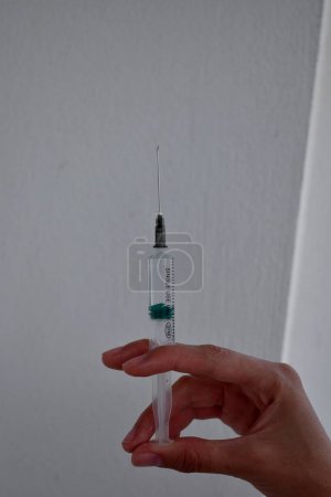Photo for Syringe with medicine pointing up in a woman's hand - Royalty Free Image