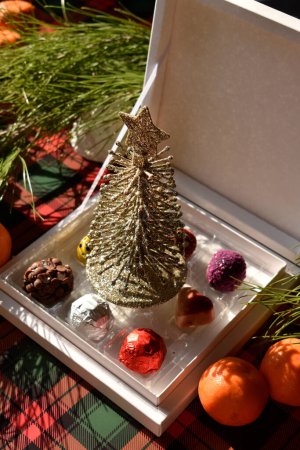 Photo for Decorative christmas tree on box among chocolate bars - Royalty Free Image