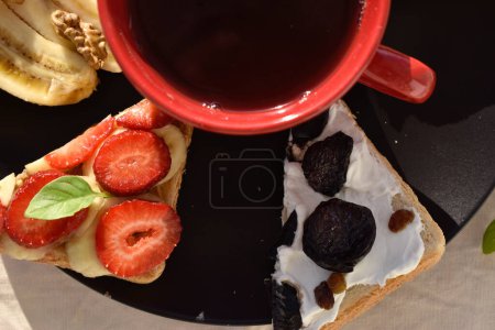 Foto de Close up red cup with tea among different fruits toasts, top view - Imagen libre de derechos