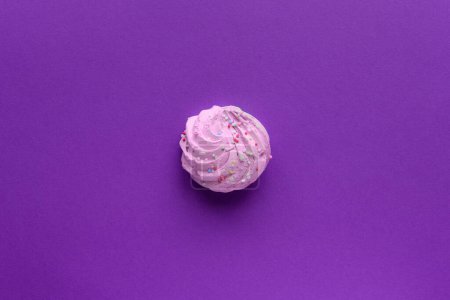 Téléchargez les photos : Nature morte d'une meringues très colorées, avec des saupoudres colorées sur, placé sur un fond violet. Une seule meringue violette se trouve au milieu du cadre. Beaucoup d'espace de copie autour. - en image libre de droit
