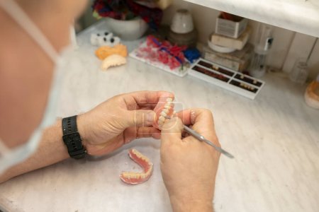 Téléchargez les photos : Fabrication de prothèses dentaires. Les mains de l'orthopédiste font des prothèses de la mâchoire. - en image libre de droit