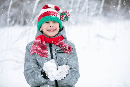 Photo for Portrait of a boy in a winter hat. Winter, outside, snow. A child plays with snow. Happy child in winter. - Royalty Free Image