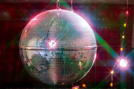 Disco ball with bright beams, night party background photo.