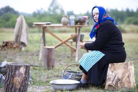 Téléchargez les photos : Biélorussie, région de Gomel, 20 juillet 2022. Camp de réfugiés. Une réfugiée épluche des pommes de terre dehors. - en image libre de droit