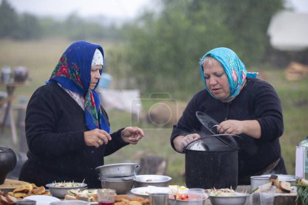 Téléchargez les photos : Biélorussie, région de Gomel, 20 juillet 2022. Camp de réfugiés. Femmes et hommes réfugiés préparent leur nourriture à l'extérieur dans un camp de réfugiés. - en image libre de droit