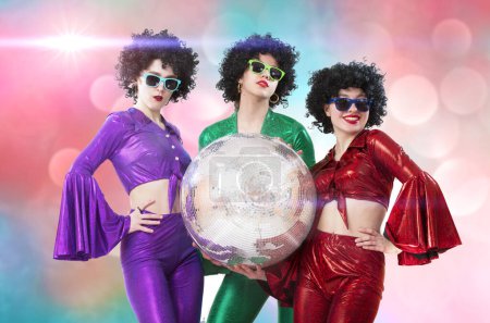 Téléchargez les photos : Groupe de filles funky tenant une boule disco, fête d'Halloween, sur un fond rose. - en image libre de droit