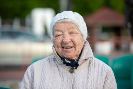 Photo for Elderly woman with wrinkles in a knitted hat, smiling, looking at the camera. An eighty-five year old woman. - Royalty Free Image