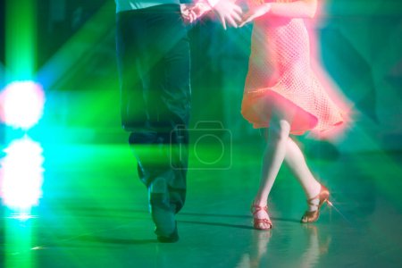 Foto de Fondo abstracto del baile de salón en los rayos de la iluminación del escenario. Las piernas de los bailarines hacen movimientos de baile. - Imagen libre de derechos