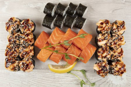 Foto de Conjunto de varios rollos de sushi sobre un fondo de madera blanca. Comida japonesa. - Imagen libre de derechos