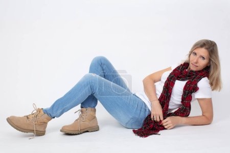 Adult beautiful slender woman in jeans and boots posing while lying in the studio.