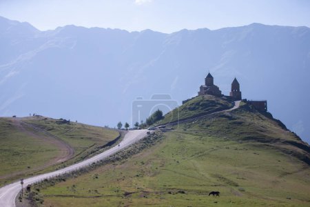 Foto de Vista cercana de la iglesia de la Santísima Trinidad en la cordillera de Kazbegi cerca de Stepantsminda vista de las montañas del Cáucaso en el fondo - Imagen libre de derechos