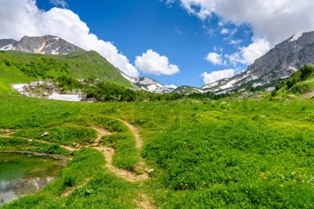 Mountain hiking trail. Beautiful landscape with mountains, green grass meadows and hiking trail in springtime.