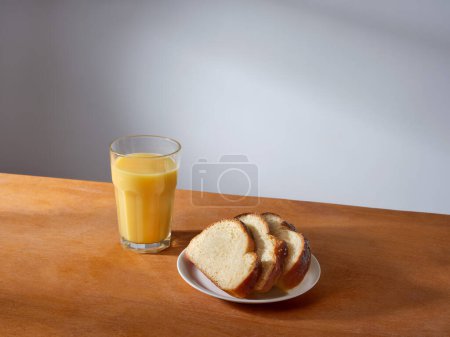 Foto de Breakfast with a glass of fresh-pressed orange juice and some slices of brioche bread - Imagen libre de derechos
