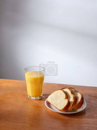 Téléchargez les photos : Breakfast with a glass of fresh-pressed orange juice and some slices of brioche bread - en image libre de droit