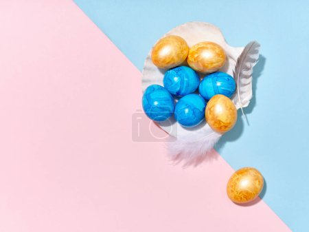 Téléchargez les photos : Mise en page créative avec des œufs de Pâques colorés disposés dans un coquillage sur fond bleu vif et rose. Un modèle de contenu festif - en image libre de droit