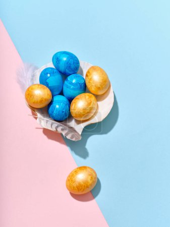 Téléchargez les photos : Creative layout with colored easter eggs arranged in a seashell on bright blue and pink background. A template for festive content - en image libre de droit
