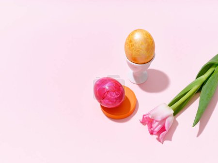 Foto de Creative layout with colored red and golden easter eggs and a tulip on bright pink background. Festive imagery concept - Imagen libre de derechos