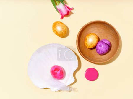 Foto de Flat lay still life with colored easter eggs and pink tulips on bright yellow sunlit background. - Imagen libre de derechos