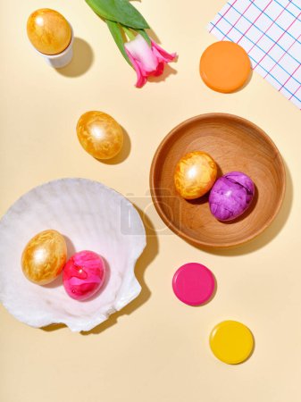 Foto de Plano ponen bodegón con huevos de Pascua de colores y tulipanes rosados sobre fondo amarillo brillante soleado. - Imagen libre de derechos