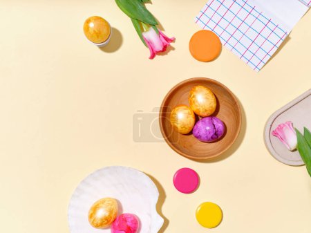 Photo for Flat lay still life with colored easter eggs and pink tulips on bright yellow sunlit background. - Royalty Free Image