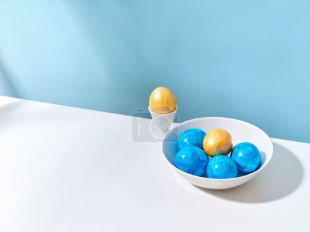 Foto de Creative layout with colored blue and golden easter eggs on bright background. A template for festive content - Imagen libre de derechos