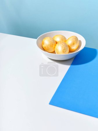Foto de Creative layout with colored blue and golden easter eggs on bright background. A template for festive content - Imagen libre de derechos