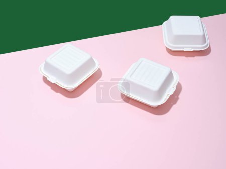 Foto de Envases ecológicos para entrega de alimentos. Hamburguesa cajas para llevar sobre fondo verde y rosa - Imagen libre de derechos