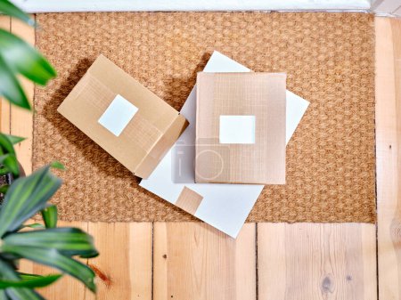 Téléchargez les photos : Empilement de colis en carton livrés sur un tapis de porte à côté de l'entrée de l'appartement - en image libre de droit