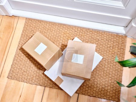 Photo for Stack of delivered cardboard parcels on a door mat next to apartment entrance - Royalty Free Image