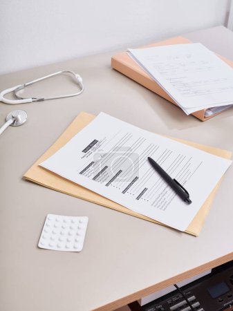 Téléchargez les photos : Par-dessus la paperasse médicale allongée sur la table du médecin - en image libre de droit