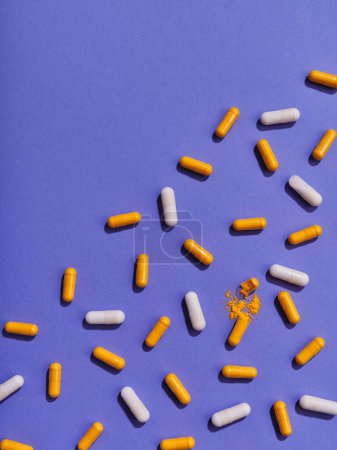 Foto de Pastillas de vitaminas naranja y blanca sobre fondo violeta - Imagen libre de derechos