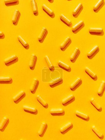 Foto de Varias píldoras de suplementos alimenticios sobre fondo amarillo - Imagen libre de derechos