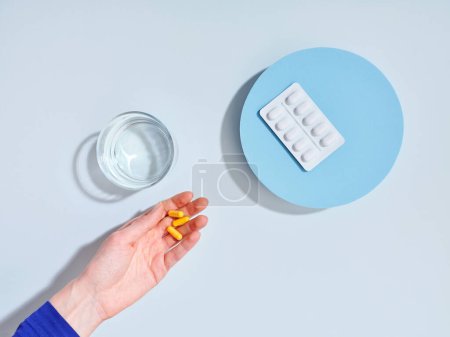 Photo for Creative composition with food supplement pills, glass of water and female hand on colorful background - Royalty Free Image