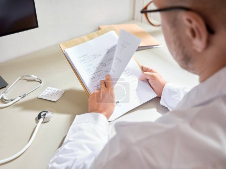 Foto de Profesional médico masculino revisando el papeleo del paciente en un hospital - Imagen libre de derechos