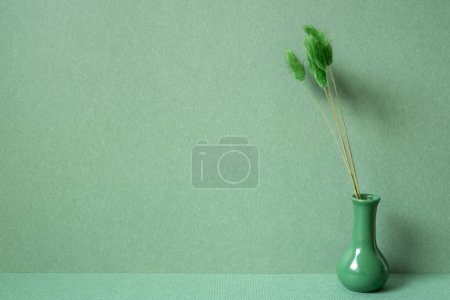 Téléchargez les photos : Vase de Lagurus ovatus sur la table. fond de mur vert. intérieur minimal - en image libre de droit