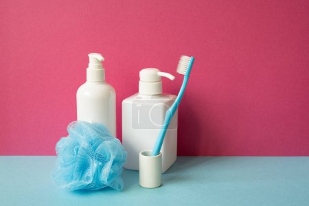 Téléchargez les photos : Objet salle de bain. Shampooing et distributeur de savon, brosse à dents, boule de douche sur étagère bleu ciel. fond mural rose - en image libre de droit