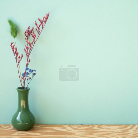 Vase of dry flower on wooden shelf. mint wall background