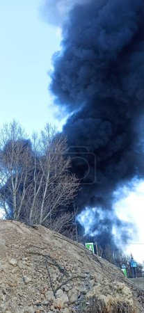 Téléchargez les photos : Smoke from fire on outskirts of the city after an air strike by Russian aircraft on the city. Horrors of war in Ukraine. Black smoke against sky. Fire during the war. Disaster - en image libre de droit